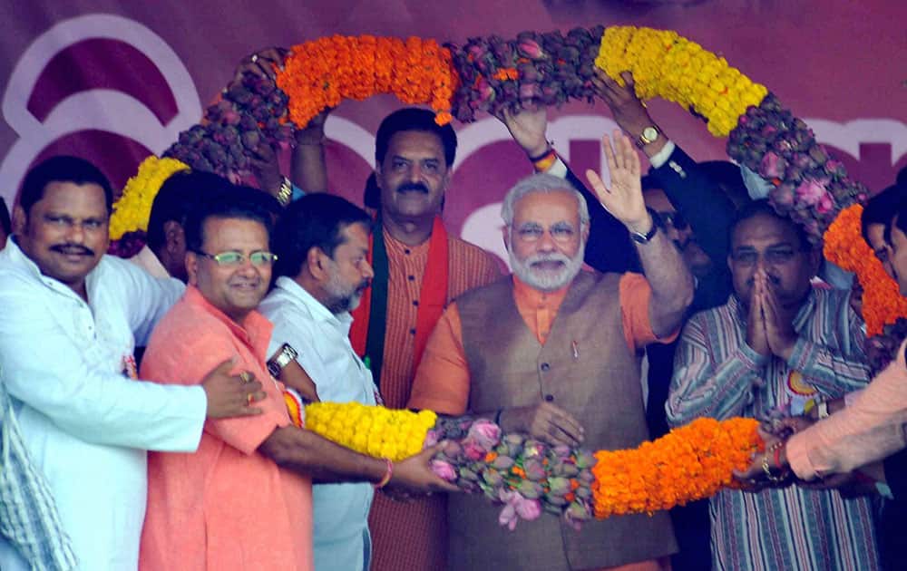 BJP`s PM candidate Narendra Modi waves as Odisha state unit president, K V Singhdeo with other leaders garland him during an election rally in Sambalpur, Odisha.