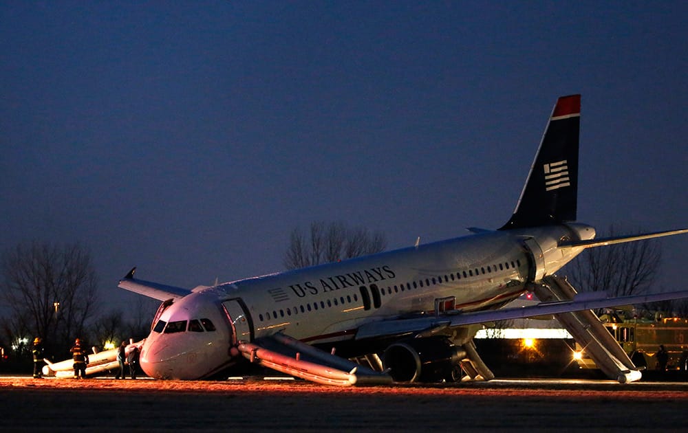 Investigators work near a damaged US Airways jet at the end of a runway at the Philadelphia International Airport in Philadelphia. Airline officials said the flight was heading to Fort Lauderdale, Fla., when the pilot was forced to abort takeoff around 6:30 p.m., after the front landing gear failed.