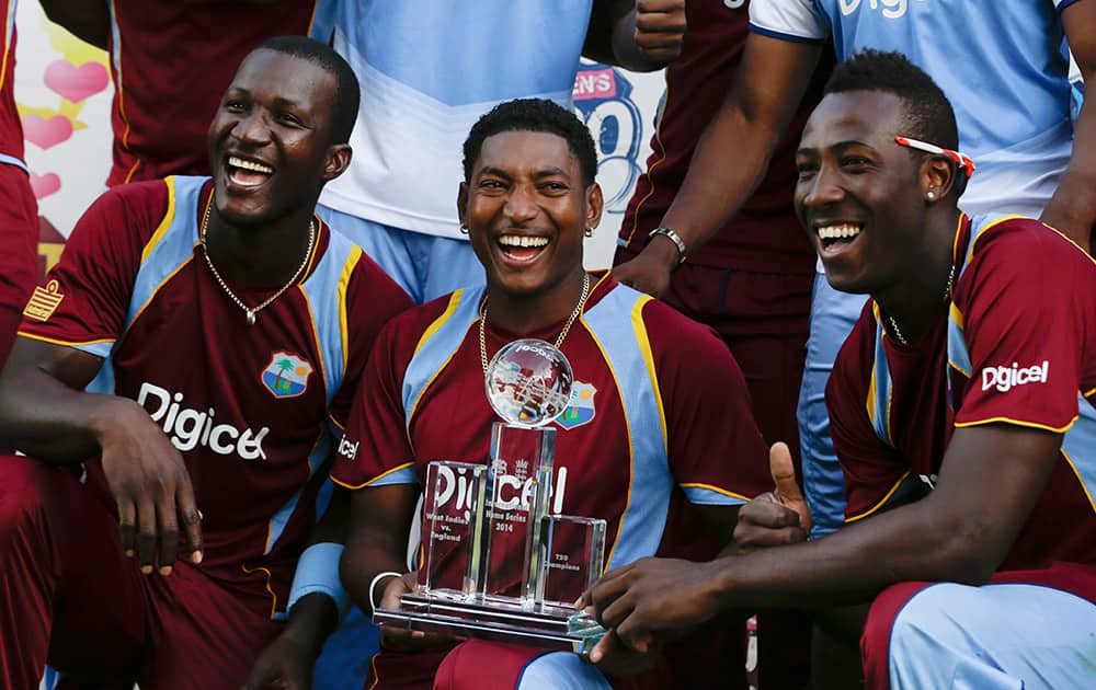 West Indies` Darren Sammy, Krishmar Santokie and Andre Russell, pose with the trophy after beating England 2-1, in the series of three T20 International cricket matches at the Kensington Oval in Bridgetown, Barbados.