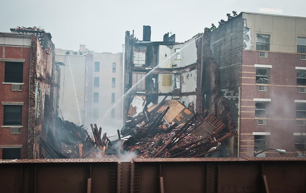 Firefighters continue to spray water on the smoldering debris from an explosion in Harlem, in New York.