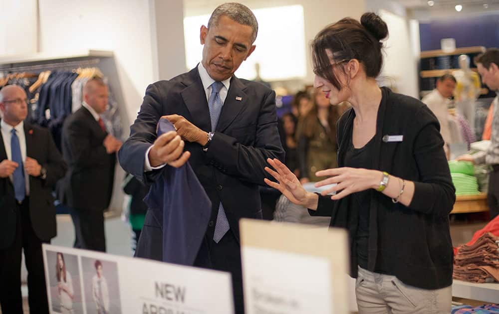 President Barack Obama, left, with the help of store employee Susan Panariello, right, shops at the GAP clothing store in Manhattan during his unannounced visit, in New York.