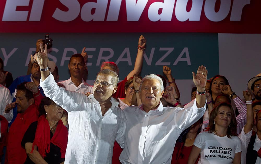 Presidential candidate Salvador Sanchez Ceren, of the ruling Farabundo Marti National Liberation Front (FMLN), right, and vice-presidential candidate Oscar Ortiz wave to supporters as they celebrate after partial results were announced by election authorities in San Salvador, El Salvador.