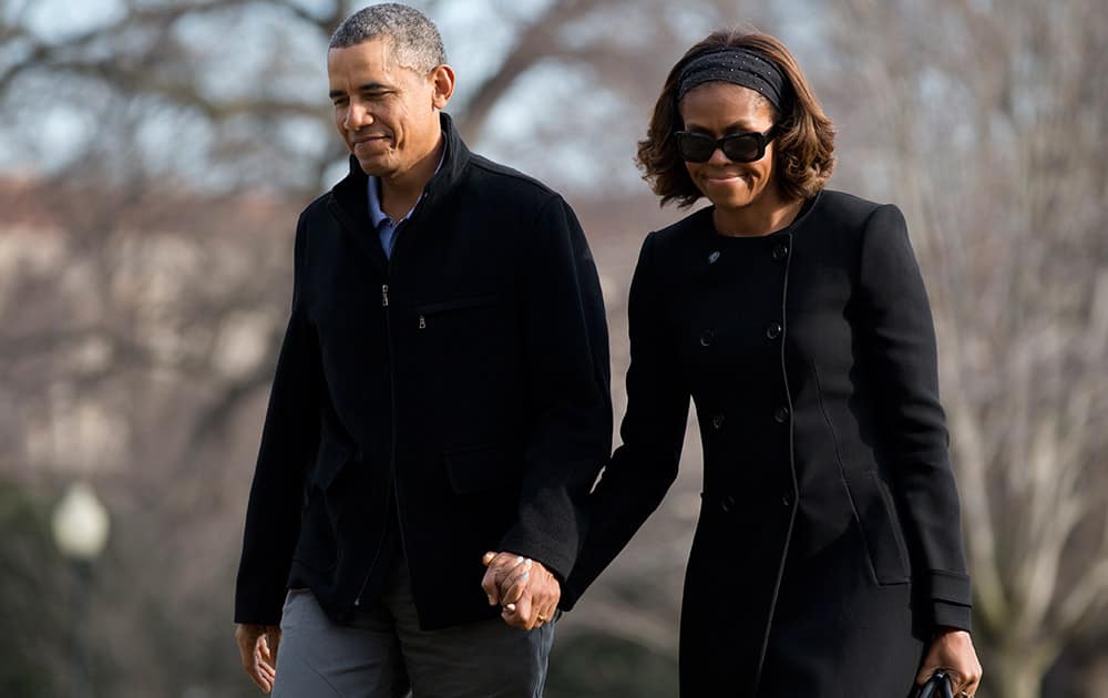 President Barack Obama and first lady Michelle Obama walk hand in hand across the South Lawn to the White House, in Washington, as they arrive from Florida.