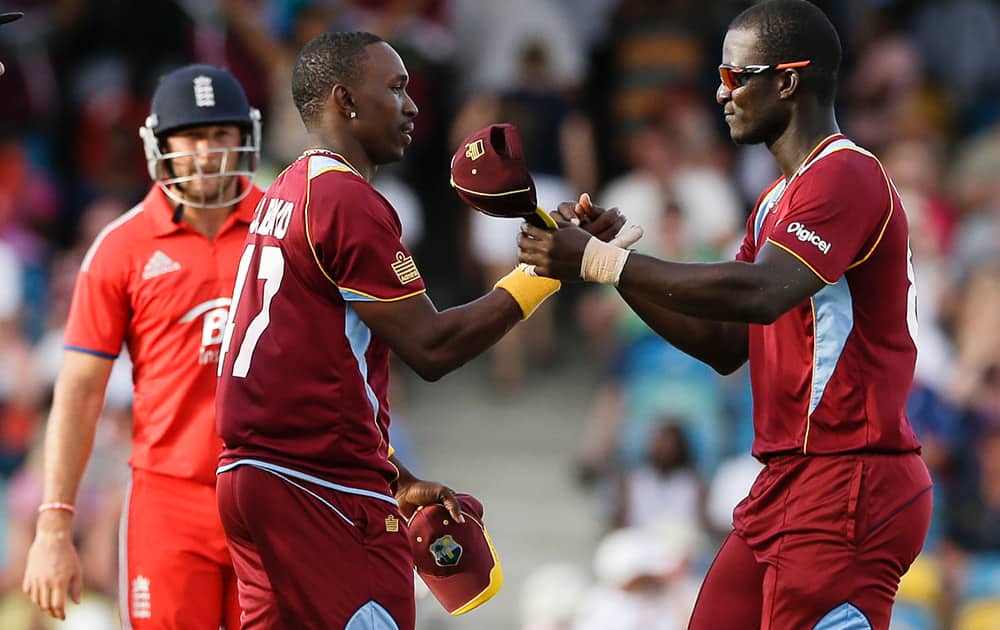West Indies` Darren Sammy, right, and Dwayne Bravow shake hands after defeating England by 27 runs during their first T20 International cricket match at the Kensington Oval in Bridgetown, Barbados.