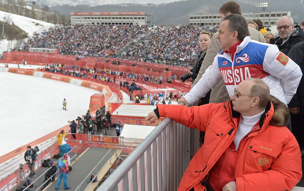 Russian President Vladimir Putin, foreground, watches downhill ski competition of the 2014 Winter Paralympics in Roza Khutor mountain district of Sochi, Russia, as Russia`s sports minister Vitaly Mutko stands behind.