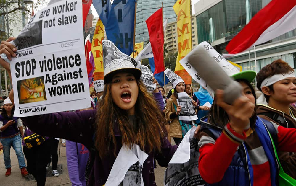 Domestic helpers and their supporters shout slogans during a rally to mark the International Women`s Day in Hong Kong.