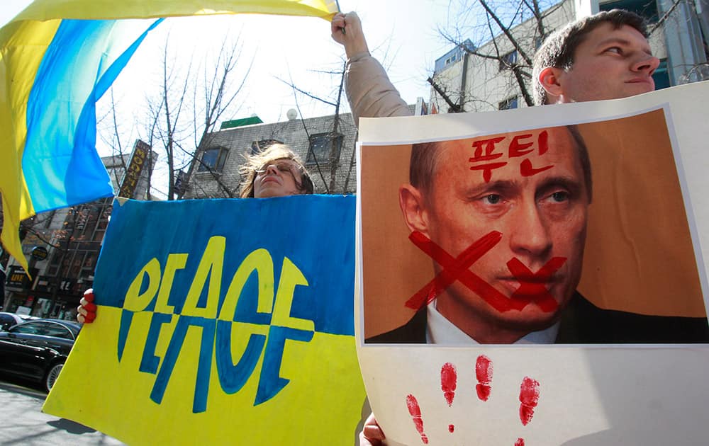 Ukrainians stage a rally to denounce Russia’s President Vladimir Putin and his military presence in Ukraine’s Crimea region, in Seoul, South Korea. The Korean word at right read `Putin`.