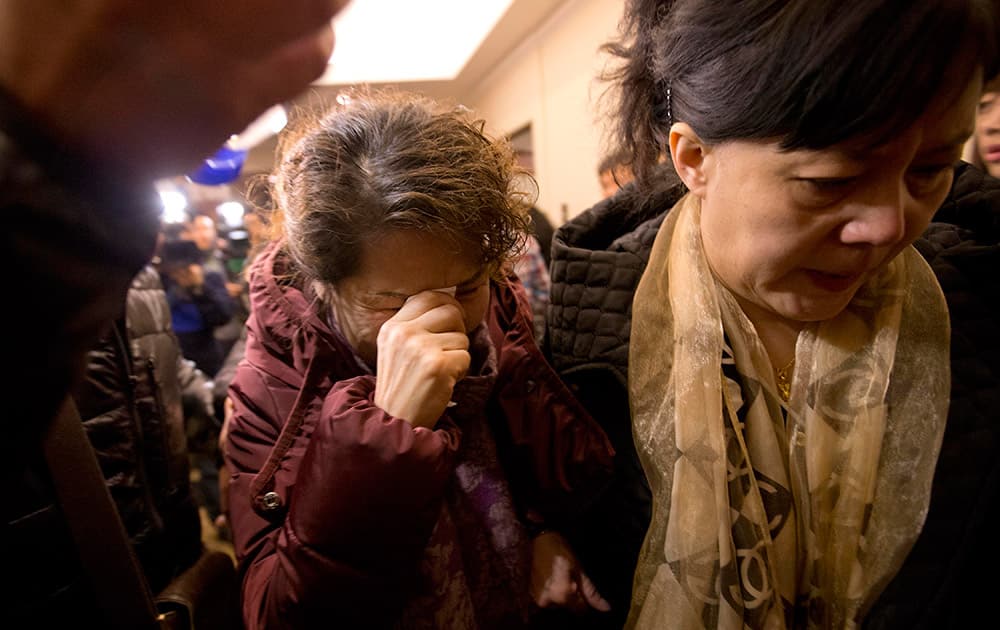 A Chinese relative of passengers aboard a missing Malaysia Airlines plane, center, cries as she arrives with others to a hotel room for relatives or friends of passengers aboard the missing airplane, in Beijing, China.