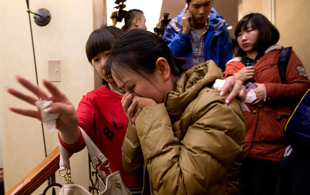 A Chinese relative of passengers aboard a missing Malaysia Airlines plane, center, cries as she is escorted by a woman while leaving a hotel room for relatives or friends of passengers aboard the missing airplane, in Beijing, China.