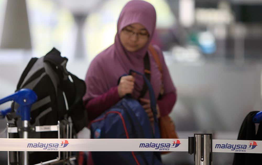 A passenger checks in at a Malaysia Airlines counter at Kuala Lumpur International Airport in Sepang, Malaysia. Planes and ships from across Asia resumed the hunt Sunday for a Malaysian jetliner missing with 239 people on board for more than 24 hours, while Malaysian aviation authorities investigated how two passengers were apparently able to get on the aircraft using stolen passports.