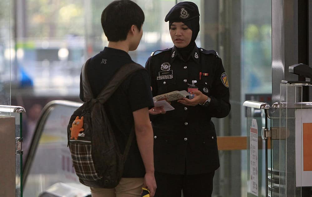A Malaysian police officer checks a passenger`s identification documents at Kuala Lumpur International Airport in Sepang, Malaysia, Sunday, March 9, 2014. Planes and ships from across Asia resumed the hunt Sunday for a Malaysian jetliner missing with 239 people on board for more than 24 hours, while Malaysian aviation authorities investigated how two passengers were apparently able to get on the aircraft using stolen passports.
