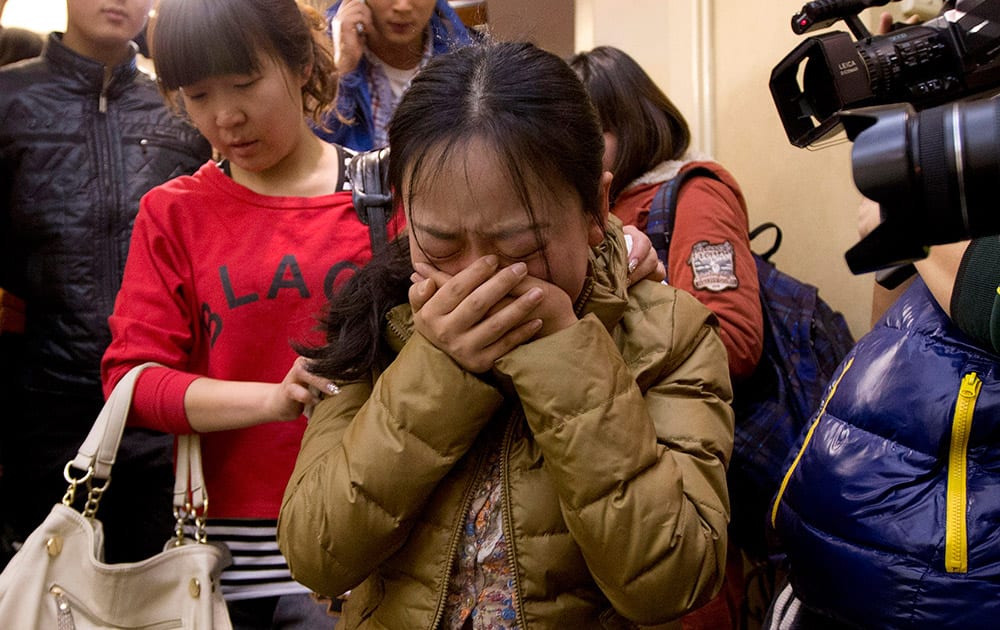 A Chinese relative of passengers aboard a missing Malaysia Airlines plane, center, cries as she is escorted by a woman while leaving a hotel room for relatives or friends of passengers aboard the missing airplane, in Beijing, China. Planes and ships from across Asia resumed the hunt Sunday for the Malaysian jetliner missing with 239 people on board for more than 24 hours, while Malaysian aviation authorities investigated how two passengers were apparently able to get on the aircraft using stolen passports.