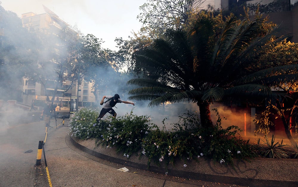 A demonstrator takes cover from tear gas fired by Bolivarian National police during clashes with anti-government protesters in Caracas,Venezuela.