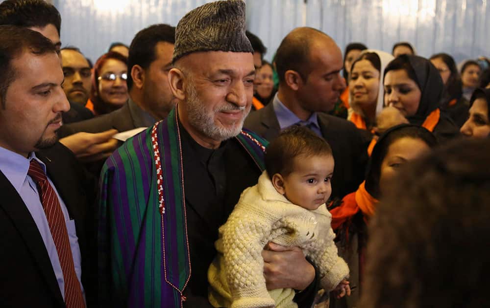 Afghan President Hamid Karzai, center, poses for a picture with a child he picked up from the crowd after delivering a speech on the occasion of the International Women`s Day at the Armani school in Kabul, Afghanistan.