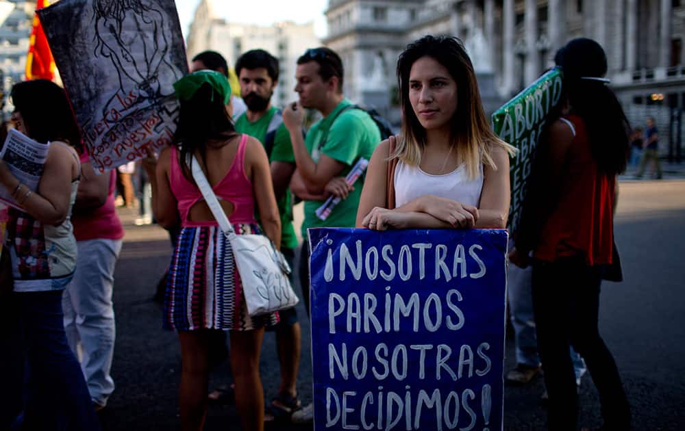 A woman holds a banner that reads in Spanish We give birth, we decide during a rally in Buenos Aires, Argentina.