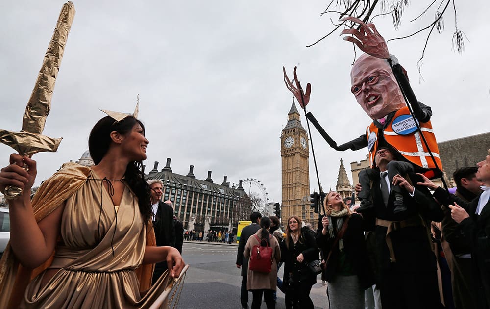 Lawyers, one dressed as Justice and one carrying a puppet depicting Chris Grayling, Britain`s Justice Secretary march to protest against legal aid cuts, across from the Houses of Parliament in central London.