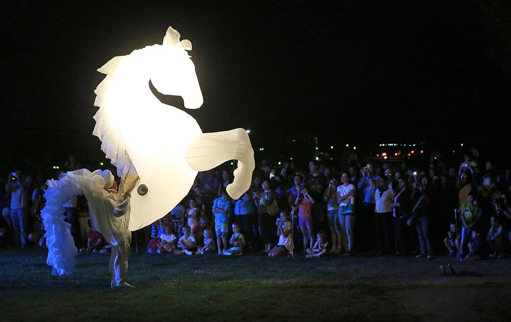 Giant inflated stallion puppets prance and perform for people during the Enlighten Festival in Canberra, Australia.