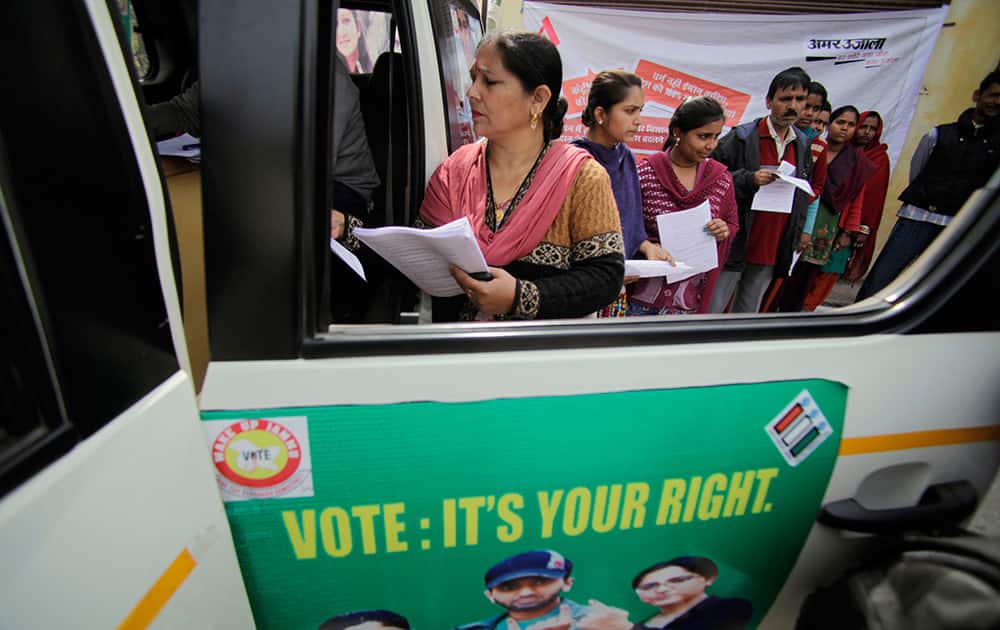 Eligible voters stand in a queue outside a vehicle to submit their applications to register themselves for the upcoming elections in Jammu.