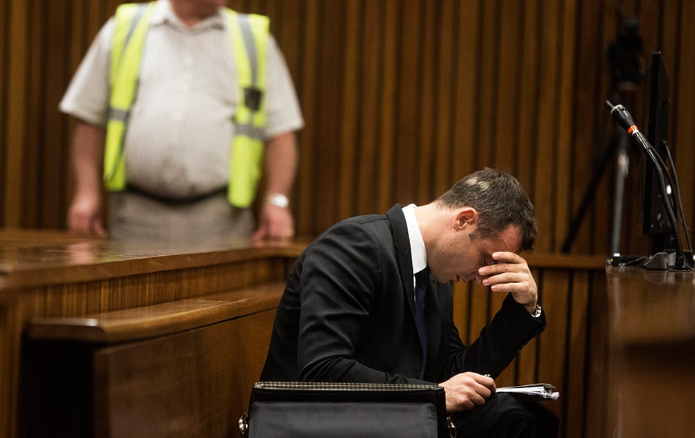 Oscar Pistorius, right, places his hand over his eyes while sitting in court on the fourth day of his trial at the high court in Pretoria, South Africa.