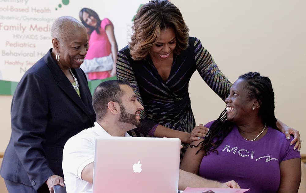 First Lady Michelle Obama talks to Affordable Care Act enrollee Kalenthia Nunnally, right, as Annie Neasman, left, and certified application counselor Paul Andres Salazar, second from left, look on at the Jessie Trice Community Health Care Center in Miami.