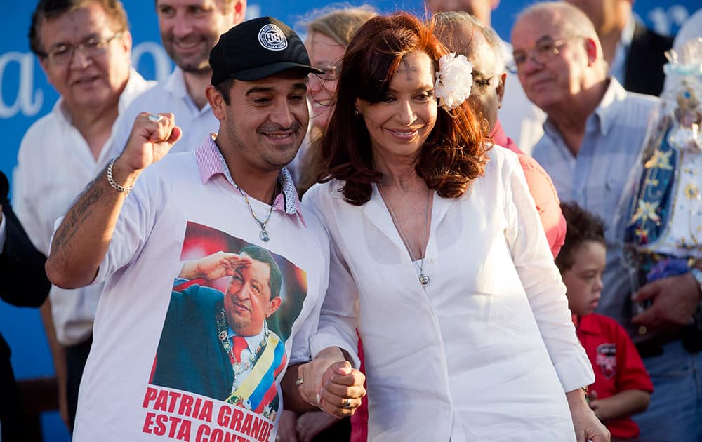 Argentine President Cristina Fernandez, right, poses with a supporter wearing a t-shirt with a photo of late Venezuelan President Hugo Chavez after a mass at the Villa 21 slum in Buenos Aires, Argentina.