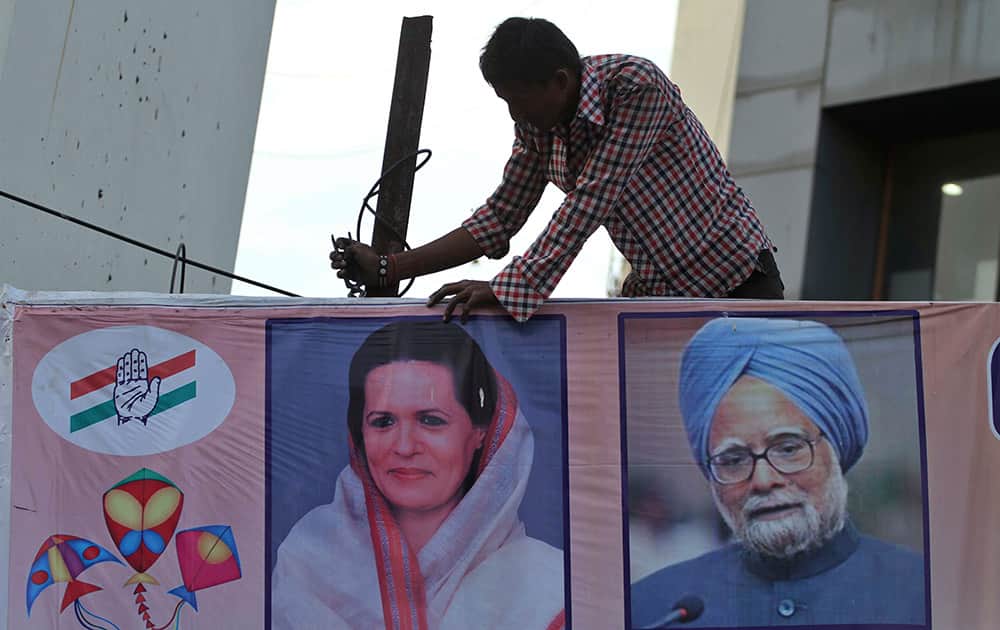A worker removes a hoarding featuring India`s ruling congress party president Sonia Gandhi and Indian prime minister Manmohan Singh, right as part of implementing the election commission`s model code of conduct in Ahmadabad.