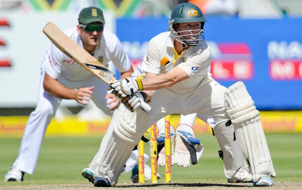 Australia`s Chris Rogers plays a shot as South Africa`s captain Graham Smith, background, look on during their third cricket test match in Cape Town, South Africa.