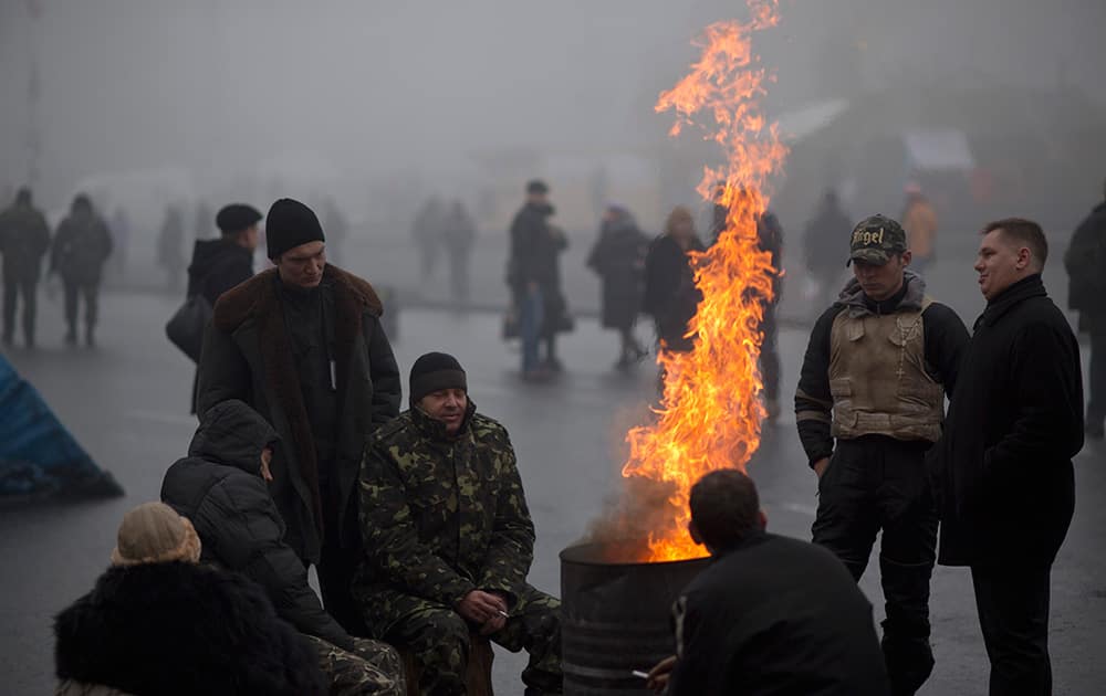 Ukrainians warm themselves next to a fire at Kiev`s Independence Square, Ukraine. Vladimir Putin ordered tens of thousands of Russian troops participating in military exercises near Ukraine`s border to return to their bases as US Secretary of State John Kerry was on his way to Kiev.