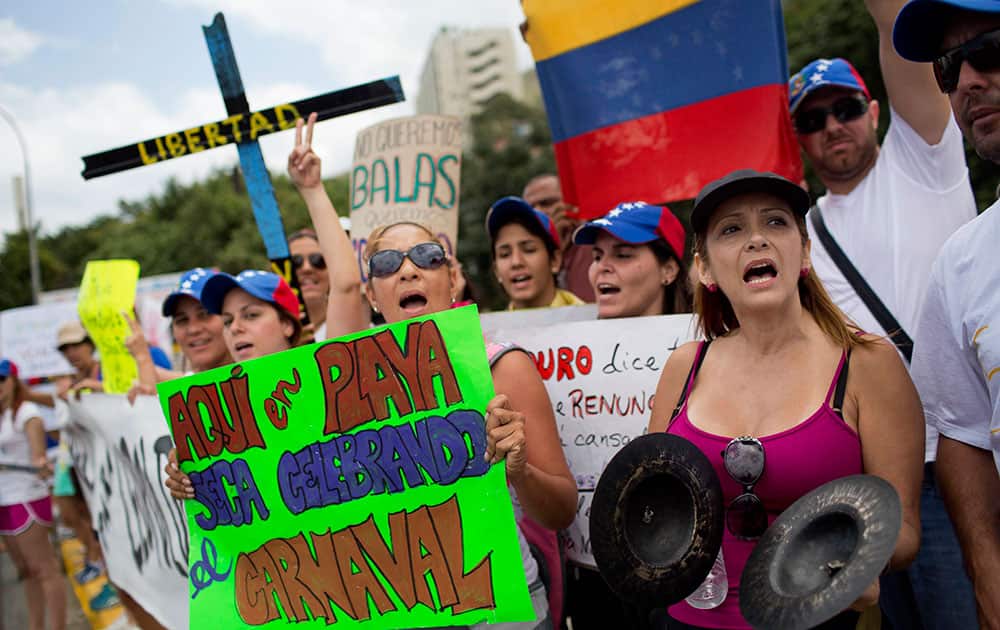 Anti-government protesters gather near the beach in La Guaira, Venezuela. The sign at left reads in Spanish `Here at the beach we`re celebrating carnival` and the cross behind reads `Liberty`.