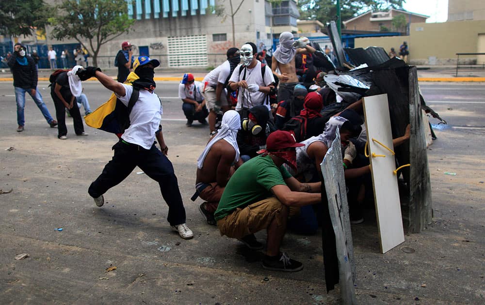 A masked demonstrator throws a stone at Bolivarian National Guards during clashes in Caracas, Venezuela.