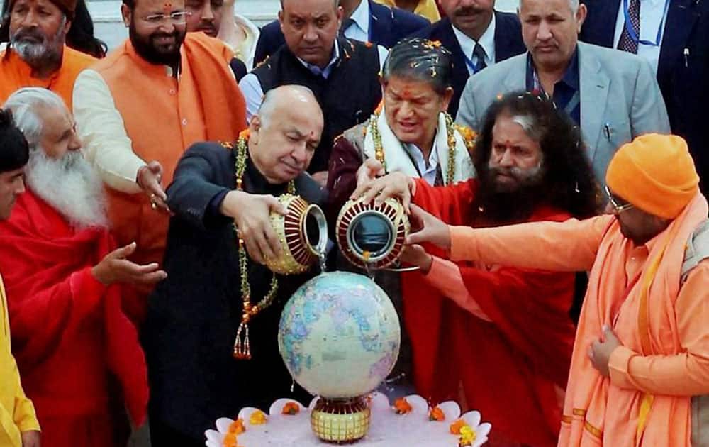Union Home Minister Sushilkumar Shinde with Uttarakhand Chief Minister Harish Rawat pour water on a globe during a function in Rishikesh.