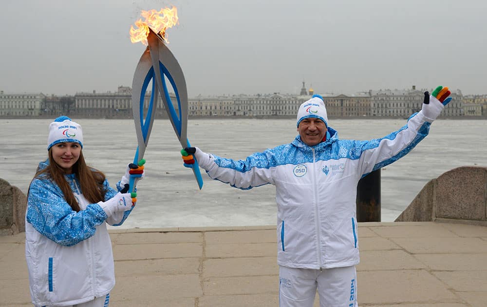 This photo provided by www.sochi2014.com torch bearers hold their torches during the Paralympic torch relay with a frozen Neva River at the background in St.Petersburg, Russia.