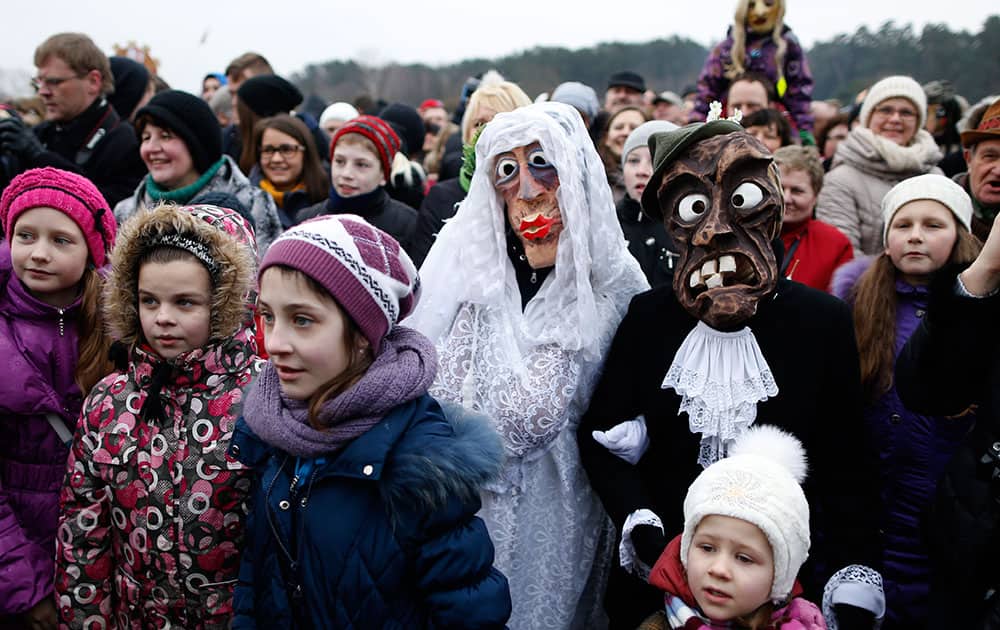People gather watch an effigy of Lady Winter burning, with one couple wearing traditional carnival masks, during Shrovetide celebrations, in the Rumsiskes village, some 89 kilometers (56 miles) north of Vilnius, Lithuania.