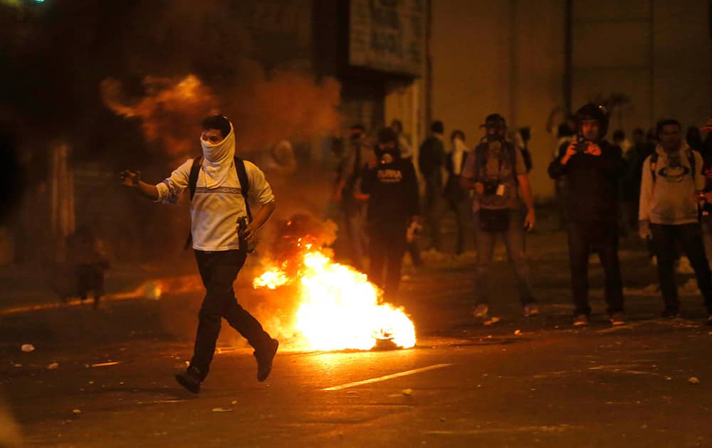 A demonstrator runs to confront a line of Bolivarian National Guard officers during anti-government protests in Caracas, Venezuela.