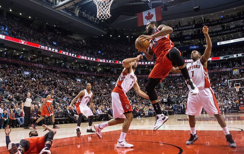 Washington Wizards` Trevor Booker, center right, takes a pass from the grounded John Wall, left, in front of the Toronto Raptors defense during first half NBA basketball action in Toronto.