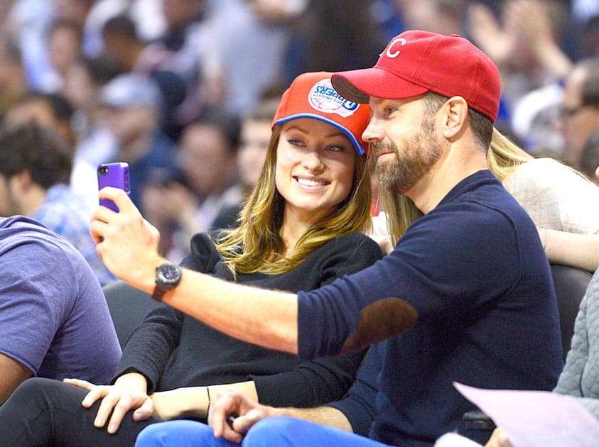 Actors Olivia Wilde and Jason Sudeikis take a picture with a fan as they watch the Los Angeles Clippers play the Houston Rockets during the first half of an NBA basketball game, in Los Angeles.
