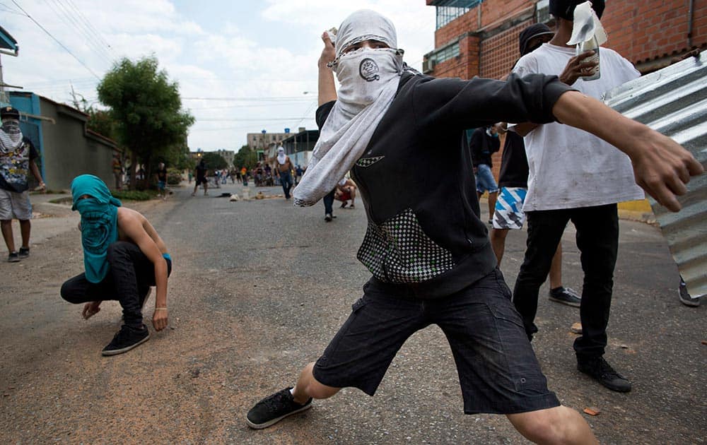 A masked demonstrator throws a rock at riot police during an anti-government protest in Valencia, Venezuela.