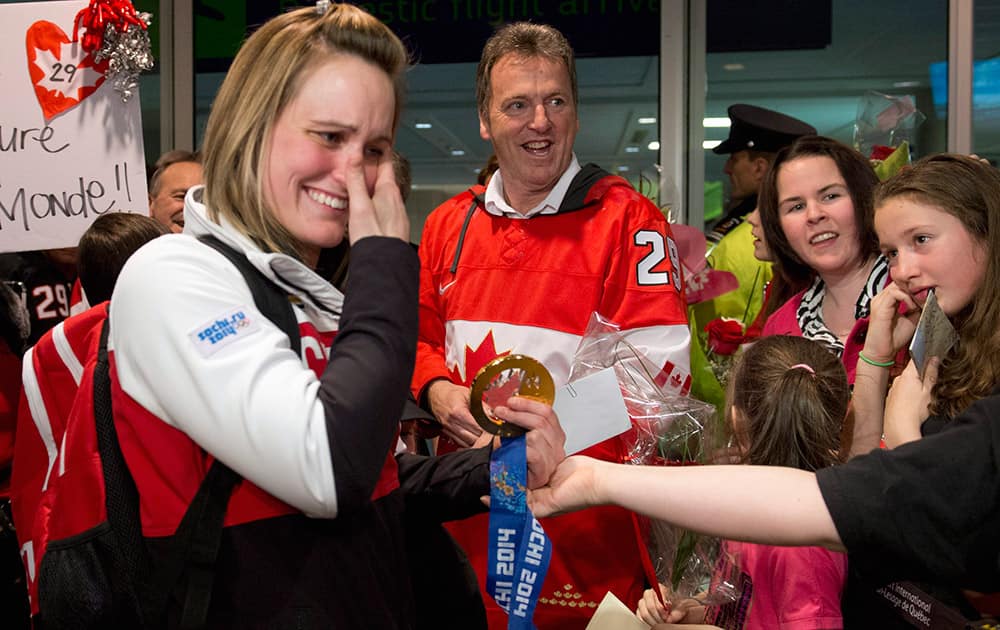 Canadian Olympic women`s hockey gold medallist Marie-Philip Poulin, left, wipes her eyes as she is welcomed by family members when arriving from the Sochi Winter Olympics, at the Jean-Lesage Airport in Quebec City. Poulin`s father Robert, behind, looks on.