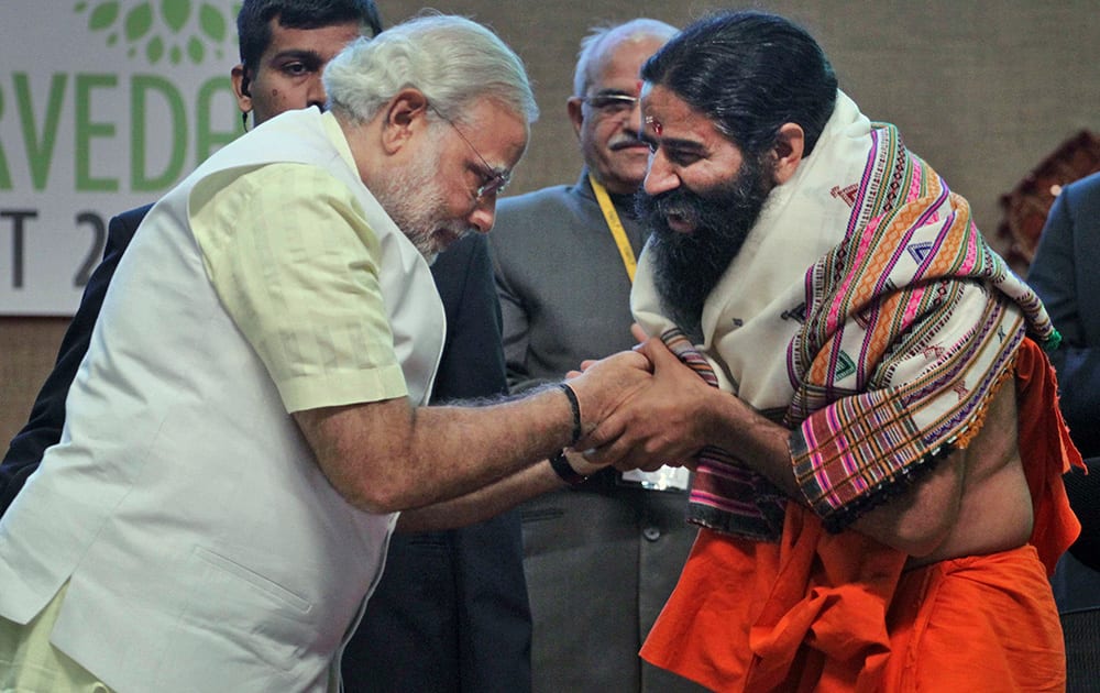 Narendra Modi presents a shawl as he greets yoga guru Baba Ramdev during the National Ayurvedic Summit in Gandhinagar.