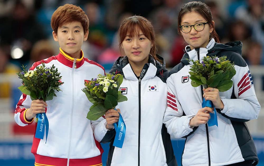 Park Seung-hi of South Korea, centre, Fan Kexin of China, left, and Shim Suk-Hee of South Korea stand on the podium during the flower ceremony for the women`s 1000m short track speedskating final at the Iceberg Skating Palace during the 2014 Winter Olympics.