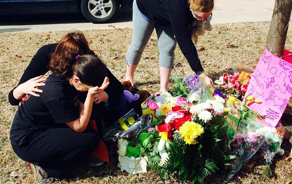 Stacey Barfield, mother of Hailey Owens, is consoled by Sara Wells, as family member Teri Nord, arranges flowers by well wishers, near the site where the 10-year-old girl was abducted just blocks from her Springfield, Mo., home.