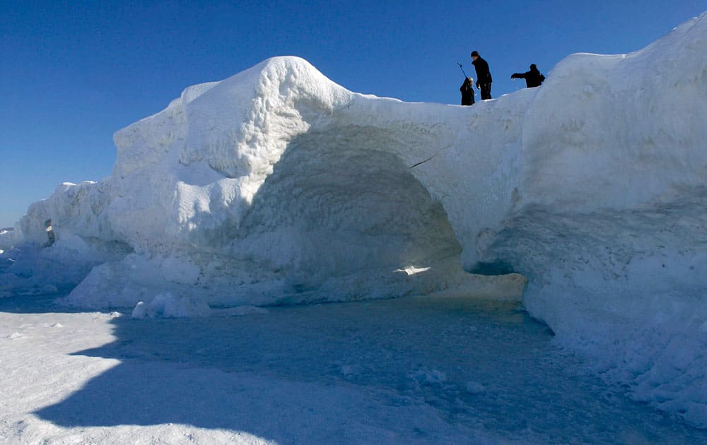 People look at an ice cave at Lake Michigan along the shore of northern Leelanau County, between Northport and Leland, Mich.