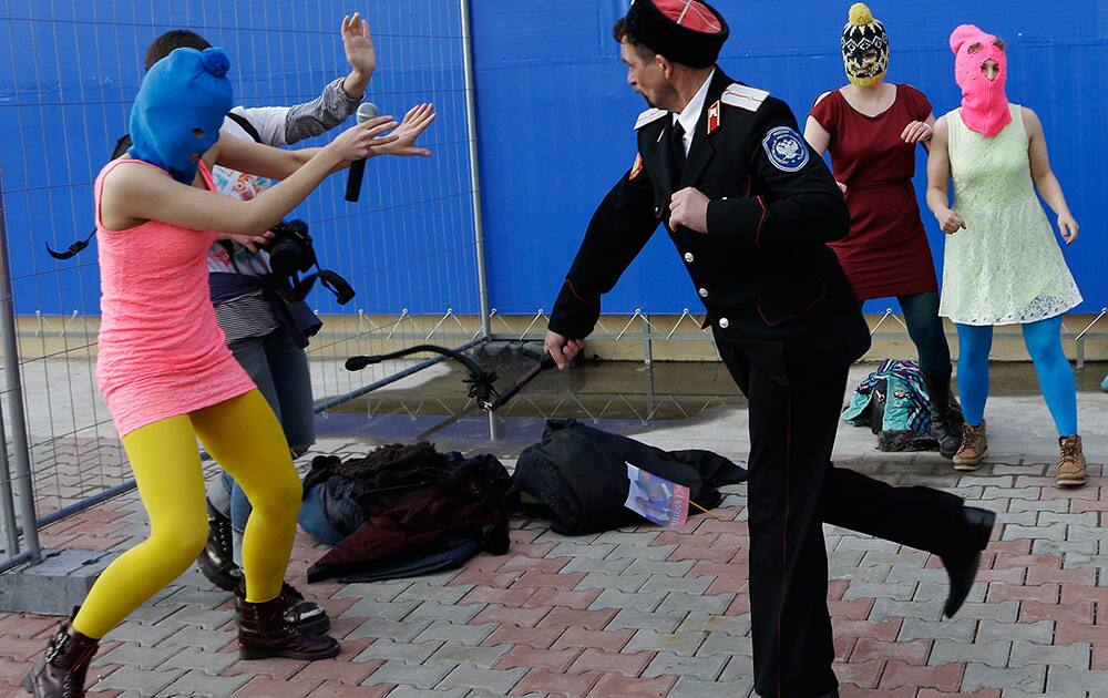 A Cossack militiaman attacks Nadezhda Tolokonnikova and a photographer as she and fellow members of the punk group Pussy Riot, including Maria Alekhina, right, in the pink balaclava, stage a protest performance in Sochi, Russia.