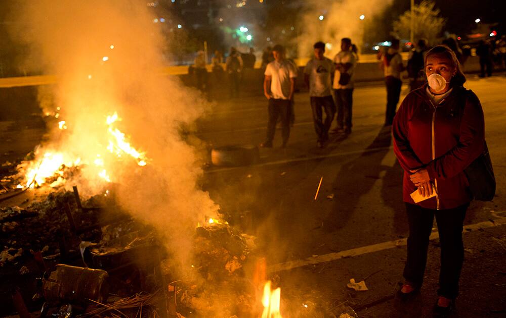A demonstrator stands next to a burning barricade during an opposition protest outside La Carlota airport in Caracas, Venezuela.