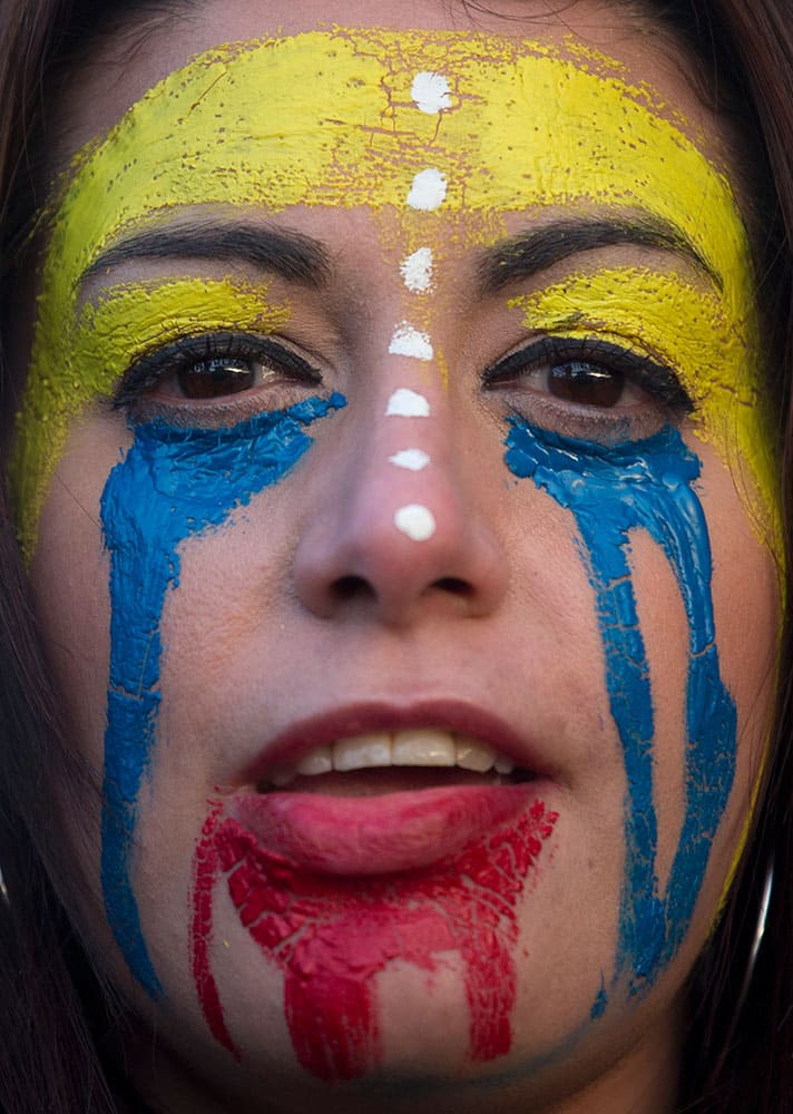 A woman with her face painted with the colors of the Venezuelan flag protests against the Venezuelan government in Madrid, Spain.