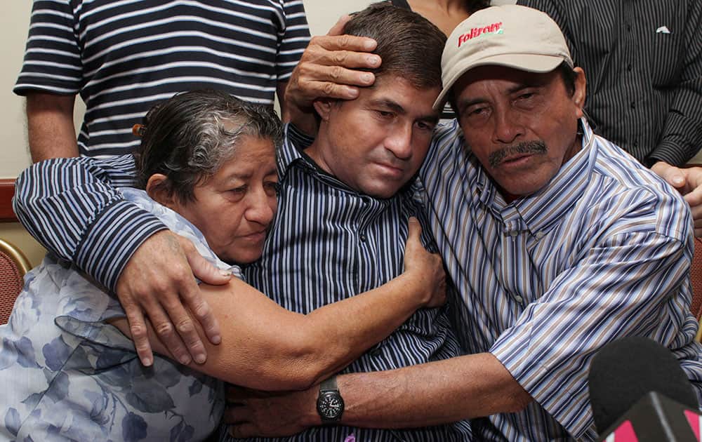 Jose Salvador Alvarenga, a fisherman who says he drifted at sea for more than a year surviving on raw fish, turtles and bird blood is embraced by his parents, Ricardo Orellana, right, and Maria Julia Alvarenga during a news conference in San Salvador, El Salvador.
