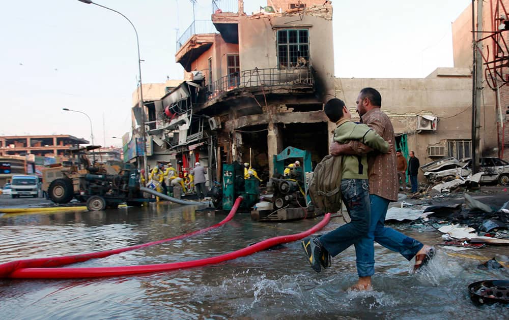 An Iraqi man helps his son who is headed to school at the site of a car bomb attack in Baghdad, Iraq.