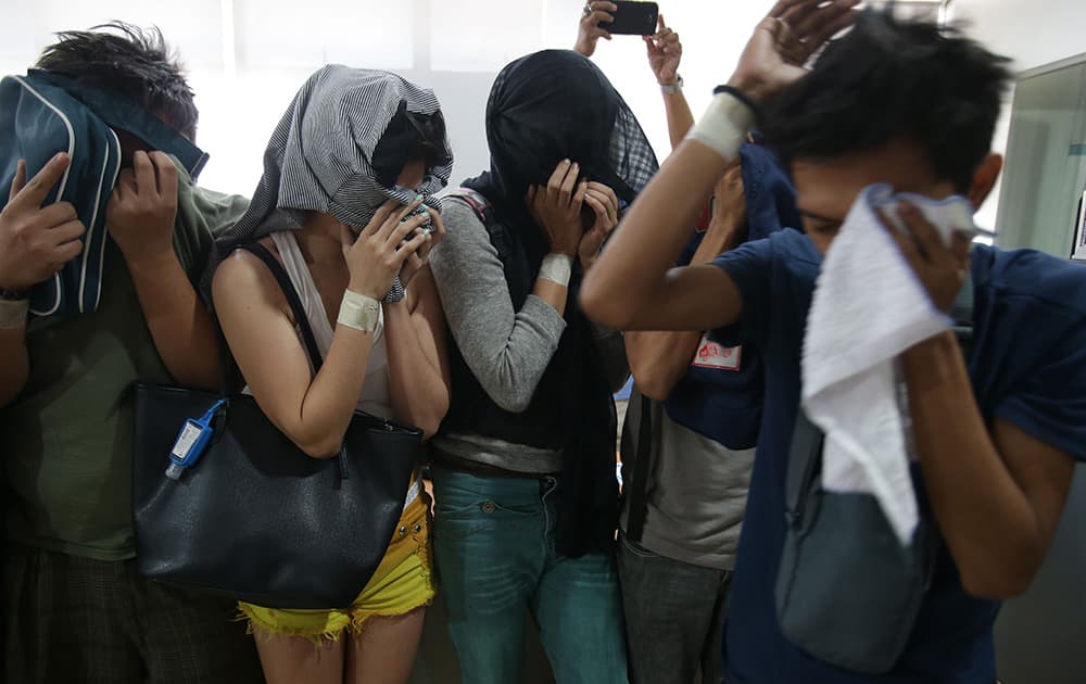 Suspects in an alleged internet porn operation cover their faces as they stay at the Cybercrime division of the National Bureau of Investigation in Manila, Philippines.