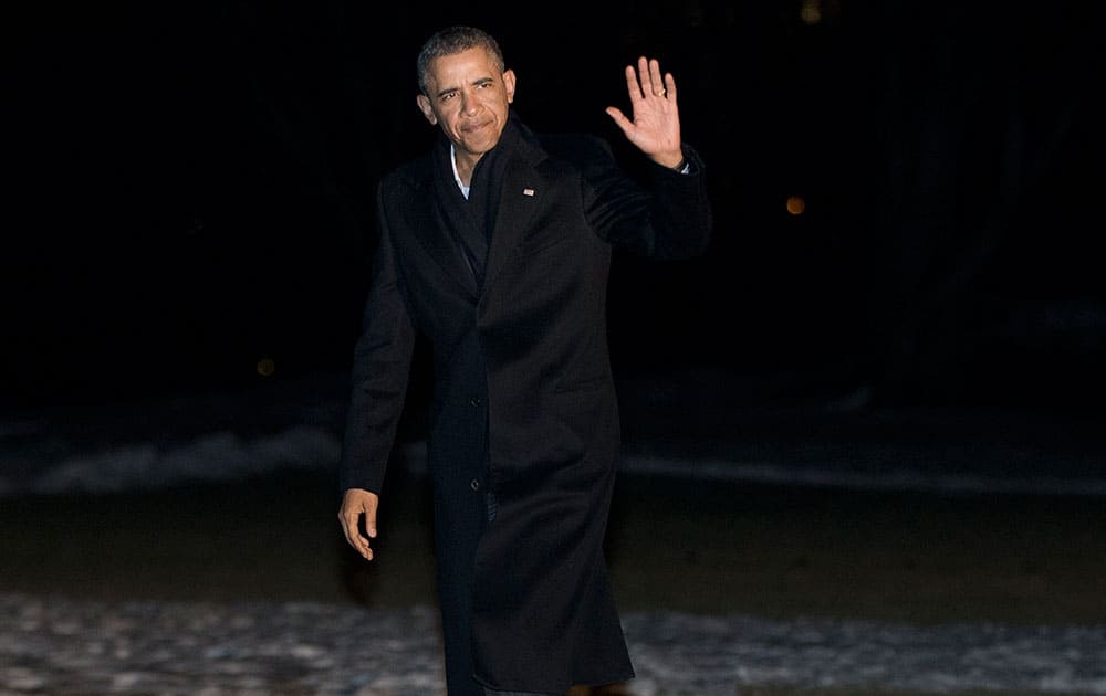 President Barack Obama waves as he walks across the South Lawn of the White House following his arrival on Marine One helicopter.