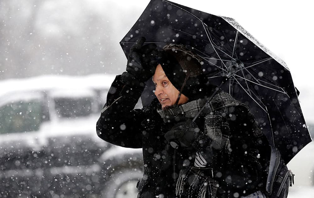 Usuddin Shaikh holds an umbrella as he waits for a bus during a heavy snowy day in Morton Grove, Ill.